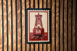 A red and white postage stamp with a red buoy and the letters "BR" printed on it, displayed on a wooden wall.