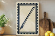 a framed print of a bow and arrow on a shelf, surrounded by kitchen utensils and a potted plant.