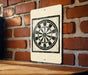 A white sign with a black and white dartboard design is mounted on a brick wall.