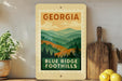 A framed poster of a mountain landscape with the text "GEORGIA" and "BLUE RIDGE FOOTHILLS" displayed on a wall.