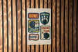 A sign with the word "BOWL" and various bowling-related icons, including bowling pins, a bowling ball, and a bowling team logo, is displayed on a wooden wall.
