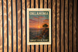 A vintage-style sign for the Sunset Vista Point in Oklahoma, featuring a scenic landscape with a sunset over a mountain range.