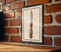a wooden table with a framed picture of a knife hanging on the wall above it.