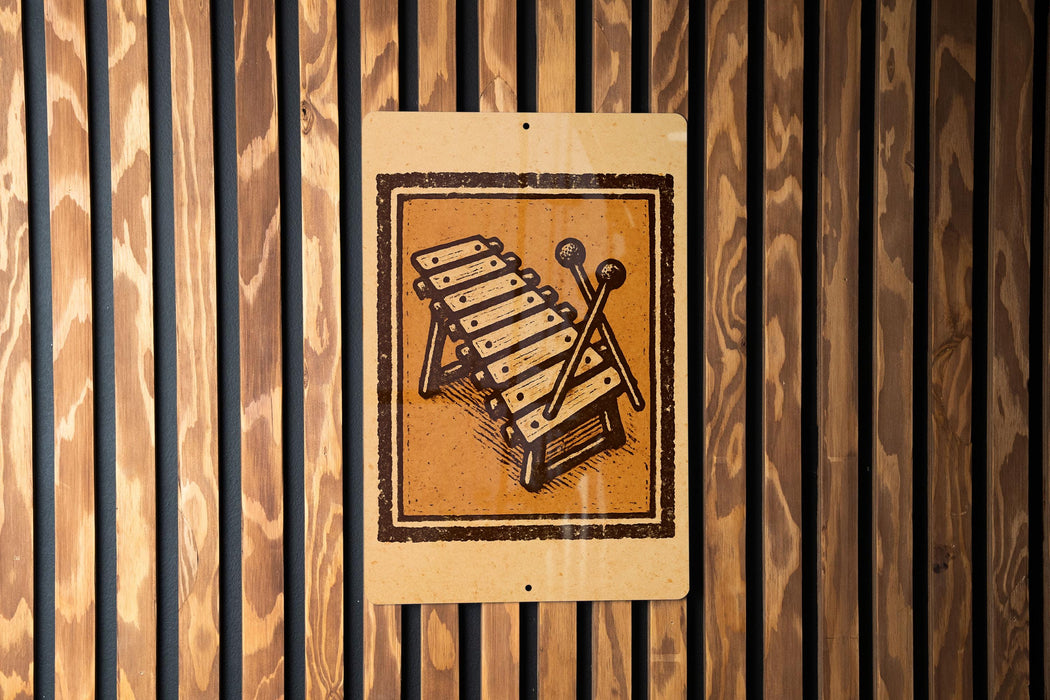 a sign with a musical instrument, specifically a xylophone, mounted on a wooden wall.