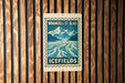 A vintage-style sign for Wrangell-St. Elias Icefields, featuring a mountain landscape and a river, is displayed on a wooden wall.