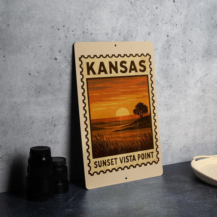 A Kansas sunset stamp or sign with a landscape image of a sunset over a field, placed on a countertop next to some black camera lenses.