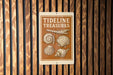 a sign with the text "TIDELINE TREASURES" and illustrations of various seashells.