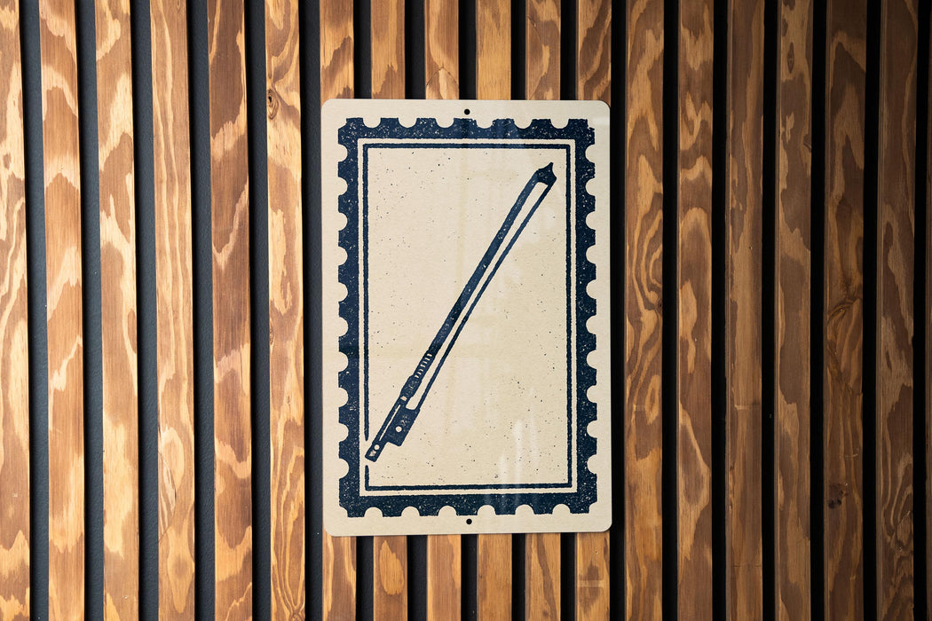 a sign with a stylized drawing of a pen or pencil on a white background, mounted on a wooden wall.