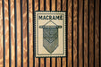 a wooden wall with a decorative sign that reads "MACRAME" in bold black letters.