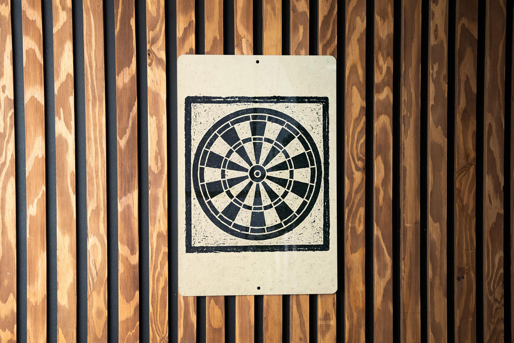 a white sign with a black and white design, which appears to be a target or a bullseye, mounted on a wooden wall.