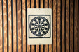 a white sign with a black and white design, which appears to be a target or a bullseye, mounted on a wooden wall.