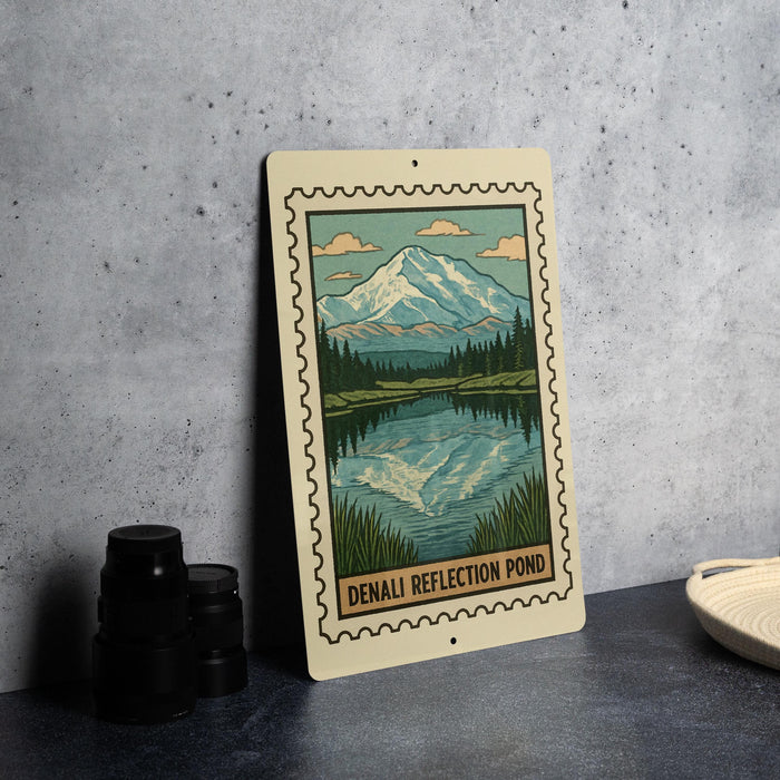 A framed illustration of a mountain landscape with a lake, depicting the Denali Reflection Pond, is displayed on a table.