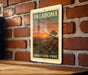 A vintage-style metal sign with the text "OKLAHOMA SUNSET Vista Point" hanging on a brick wall.