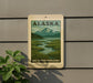 A sign for Salt Marsh Overlooks in Alaska, featuring a scenic landscape with mountains, a river, and lush vegetation.