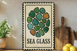 a decorative sign with a sea glass design, placed on a shelf next to a wooden cutting board and some lemons.