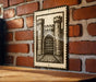 A metal sign with a castle illustration is mounted on a brick wall.