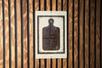 A sign with a black and white image of a cutting board is mounted on a wooden wall.