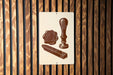 a sign with a vintage-style illustration of a seal, wax seal, and wax stamp, all depicted in brown tones against a wooden background.