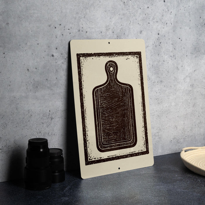 a wooden cutting board with a black and white design on it, placed on a gray countertop next to a stack of black containers and a woven basket.