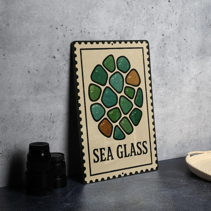 a decorative sign with a sea glass design, placed on a table next to some black camera lenses.