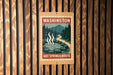 A sign for the "Hot Springs Route" in Washington, featuring a scenic illustration of a hot spring surrounded by pine trees and mountains.