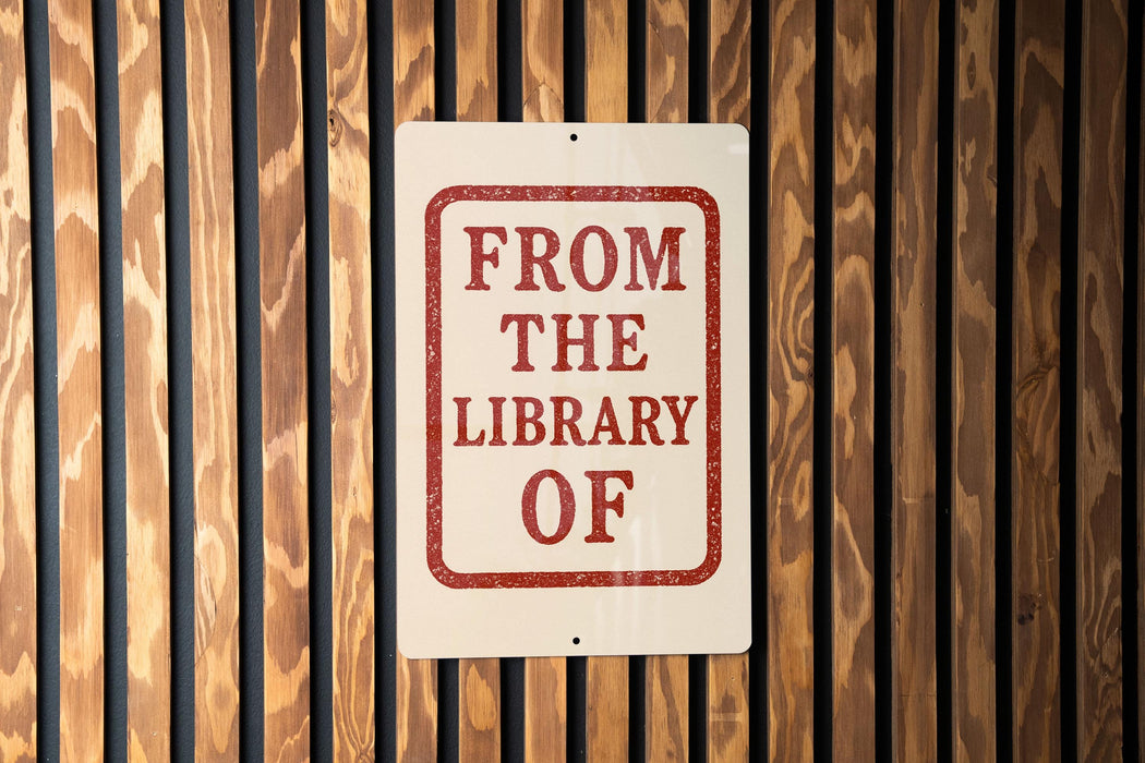 A sign that reads "FROM THE LIBRARY OF" is displayed on a wooden wall.