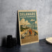 A vintage-style poster of a promenade in Delaware, featuring a couple walking along the boardwalk and a scenic view of the ocean and buildings in the background.