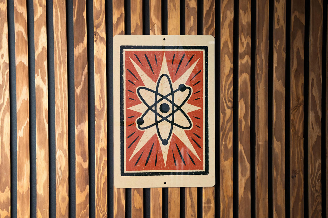 a sign with a stylized design, including a graphic of an atom and rays emanating from it, mounted on a wooden wall.