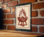 A metal sign with a red and white design depicting a fire pit or grill on a brick wall.