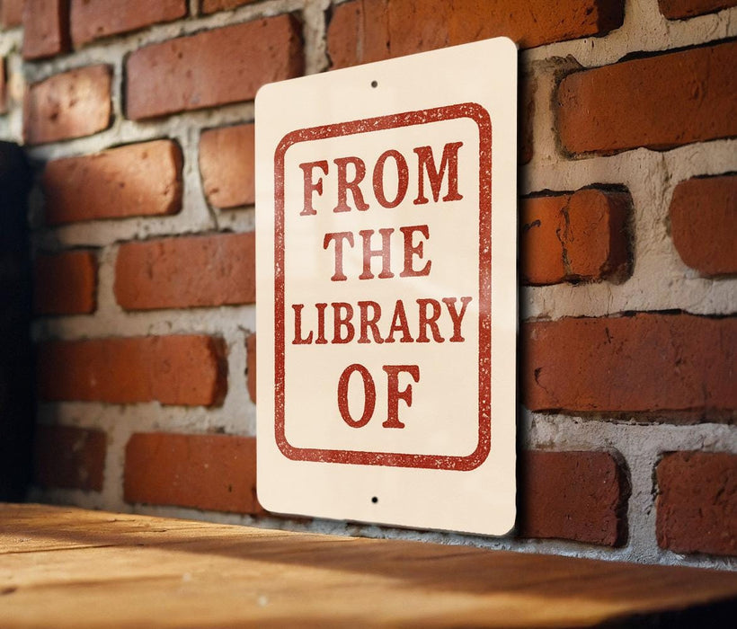 A sign on a brick wall that reads "FROM THE LIBRARY OF".