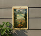 A vintage-style sign for the High Country Overlooks in Utah, featuring a scenic landscape with mountains, pine trees, and two people standing on a rock.