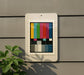 a colorful television antennae-like object mounted on a wall, with a plant to the left of the frame.