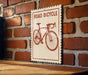 A sign with a bicycle on it is mounted on a brick wall.