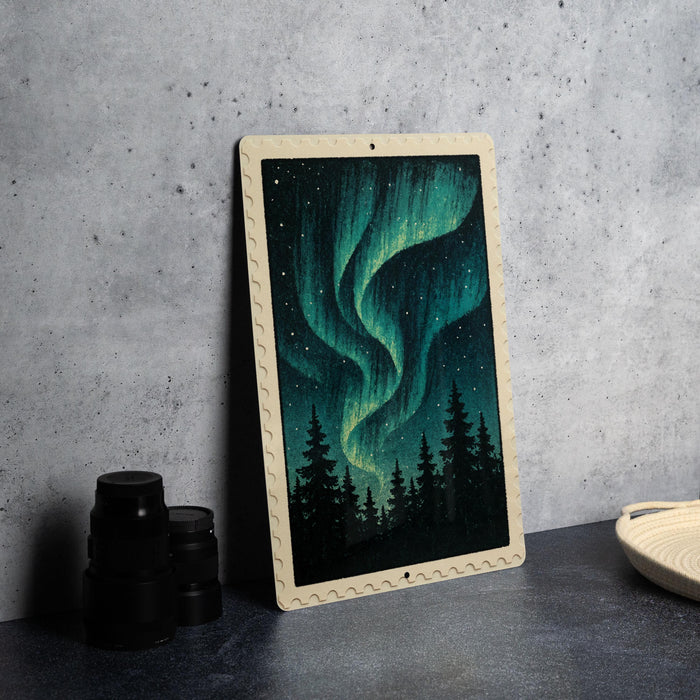 a framed painting of a night sky with a vibrant display of the Aurora Borealis, or Northern Lights, over a forest landscape.