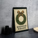 A framed illustration of a wreath with a bow on a wall, accompanied by the text "BOXWOOD WREATH" on the frame.