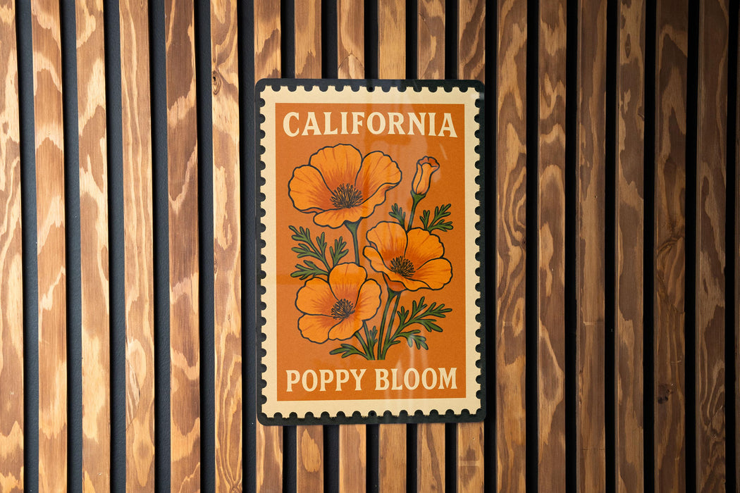 A California postage stamp featuring an illustration of orange poppies is displayed on a wooden wall.
