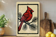a red cardinal perched on a branch, with a wooden cutting board and a potted plant in the background.