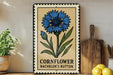 a decorative metal sign with a blue flower illustration, placed on a wooden surface next to a wooden cutting board and some lemons.