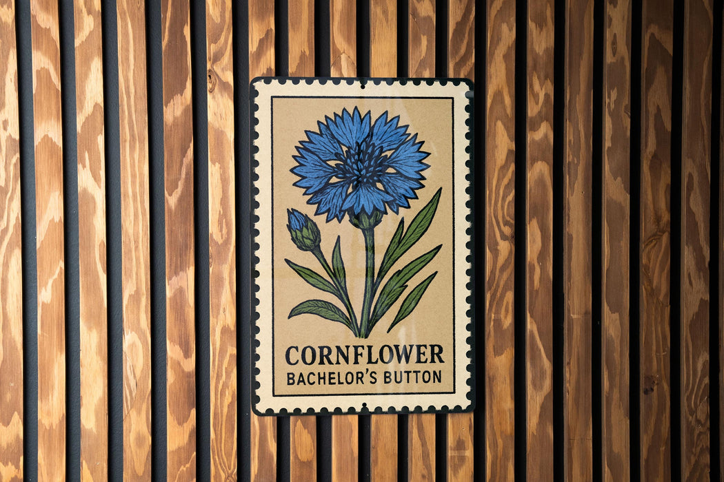 a sign with a blue flower and the text "Cornflower Baccarat Button" on a wooden background.