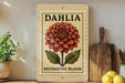 A decorative sign for the "Dahlia Decorative Bloom" is displayed on a shelf, accompanied by a potted plant, a wooden cutting board, and some lemons.