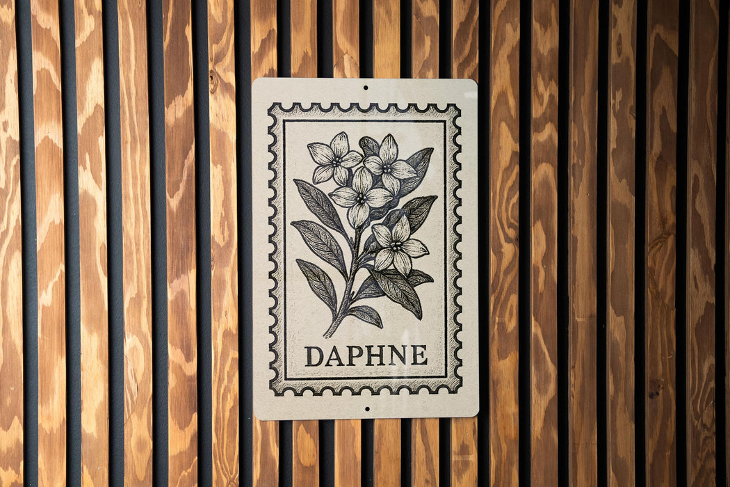 a sign with a floral design and the word "DAPHNE" printed on it, mounted on a wooden wall.