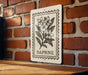 A sign with a floral illustration is mounted on a brick wall.