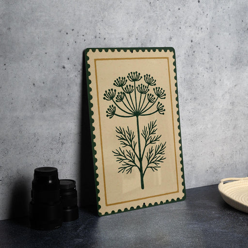 a decorative piece with a floral design on a beige background, placed on a dark surface next to a stack of black objects.