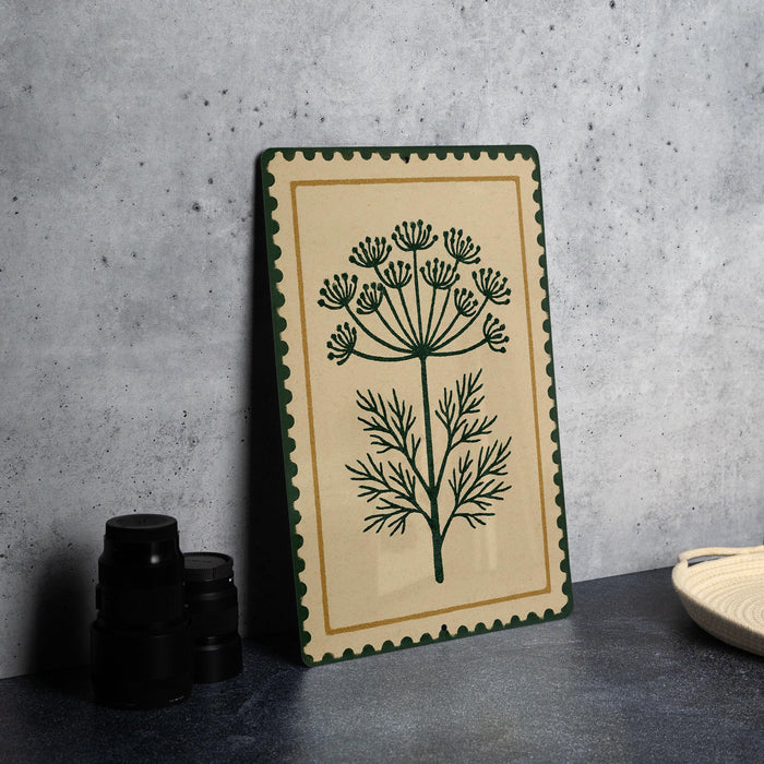 a decorative piece with a floral design on a beige background, placed on a dark surface next to a stack of black objects.