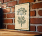 a decorative sign with a plant design, mounted on a brick wall.