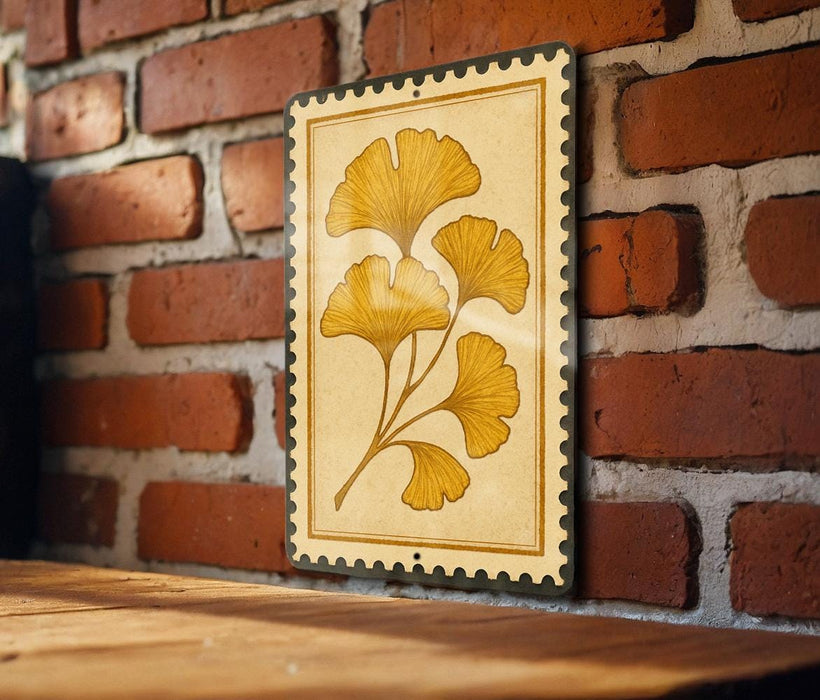 a decorative piece of art, a framed illustration of yellow ginkgo leaves, mounted on a brick wall.