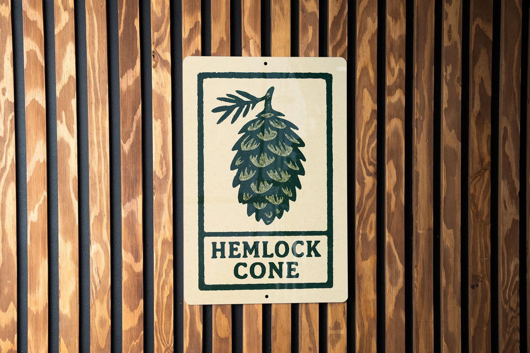 A sign with the text "HEMLOCK CONE" is displayed on a wooden wall.