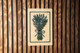 a sign with a black and white illustration of a bunch of flowers or plants, mounted on a wooden wall.