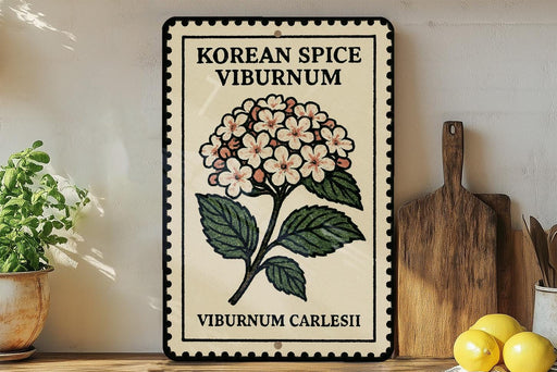 A decorative sign with a floral design and text, placed on a wooden surface next to a wooden cutting board and some potted plants.
