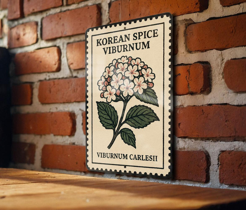 A decorative metal sign with a floral illustration and text, mounted on a brick wall.